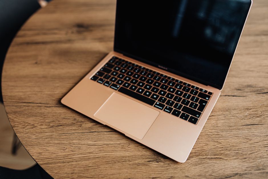 Apple MacBook Pro 35,97cm (14,2") űrfekete 1 Golden laptop on a wooden table, viewed from above, showcasing modern design and sleek aesthetics.