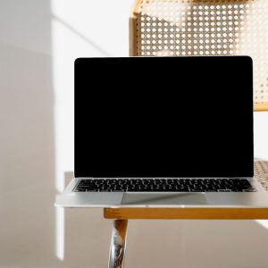 A sleek laptop sitting on a woven chair in a minimalist setting, perfect for modern workspaces.