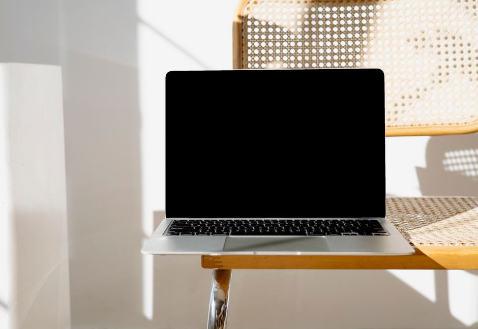 Apple MacBook Pro 35,97cm (14,2") űrfekete CTO 1 A sleek laptop sitting on a woven chair in a minimalist setting, perfect for modern workspaces.