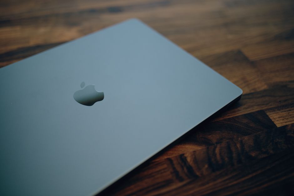 Apple MacBook Pro 14" CTO ezüst 1 Close-up of a sleek modern laptop with minimalistic design on a wooden table surface.