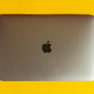 A modern laptop with a sleek design on a bright yellow surface, emphasizing minimalism.