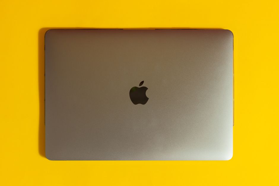 Apple MacBook Pro 41,05cm (16") ezüst 1 A modern laptop with a sleek design on a bright yellow surface, emphasizing minimalism.
