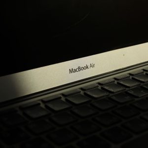 Close-up of a sunlit MacBook Air laptop showcasing its keyboard and screen with shadow effects.