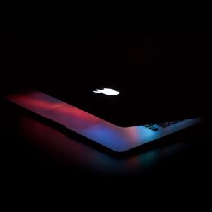 Captivating close-up of a partially open laptop with colorful lighting against a dark background.