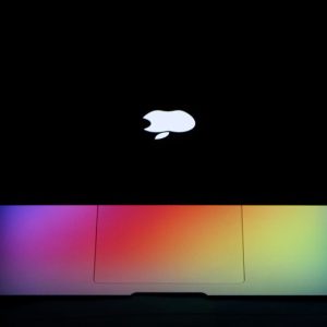 A MacBook Air with a vibrant rainbow effect on the keyboard under dark lighting showcases modern technology aesthetics.