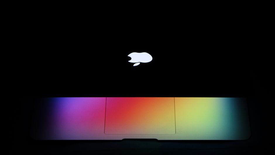 Apple MacBook Pro 35,97cm (14,2") ezüst CTO 1 A MacBook Air with a vibrant rainbow effect on the keyboard under dark lighting showcases modern technology aesthetics.