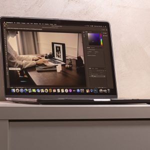 A laptop displaying a photo editing software interface on a clean, modern desk setup.