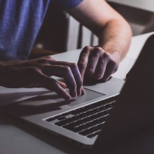 Close-up of hands typing on a laptop in a dark office setting. Perfect for business and technology themes.