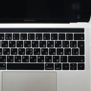 Top view of a MacBook Pro keyboard on a speckled marble surface, showcasing a Russian Cyrillic layout.