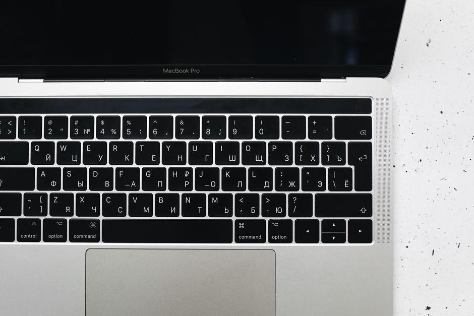 Apple MacBook Pro 35,97cm (14,2") űrfekete CTO 1 Top view of a MacBook Pro keyboard on a speckled marble surface, showcasing a Russian Cyrillic layout.