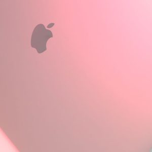 Minimalist close-up of a sleek laptop with a pink hue, perfect for modern tech aesthetics.